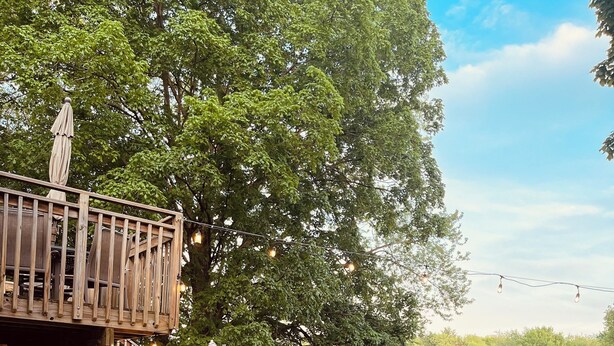 En terrass med utomhusmöbler, utsikt över en sjö och en trätrappa.