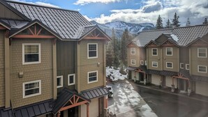 A row of multi-story buildings with a uniform architectural style, featuring brick facades, dormer windows, and a covered driveway. - Chalet 66 at the Official Collins Lake Resort (Government Camp)
