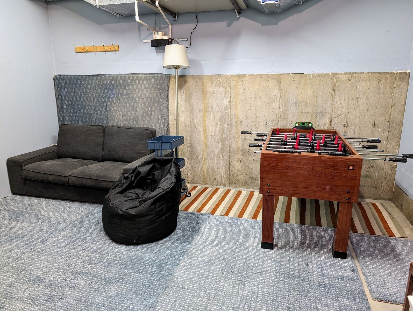 A room with a sofa, a futsal table, a black bag, and a patterned curtain.