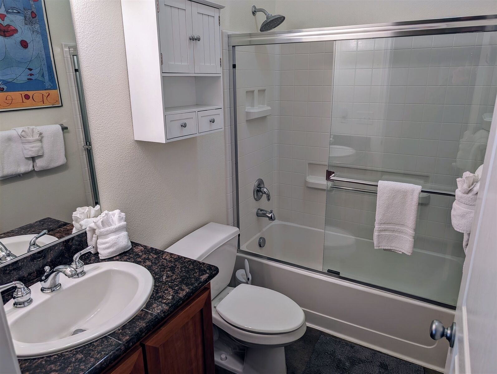 A bathroom with a sink, toilet, and glass-enclosed shower stall.