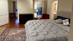 Une chambre à coucher avec un lit, une commode, une chaise, une lampe et une fenêtre.