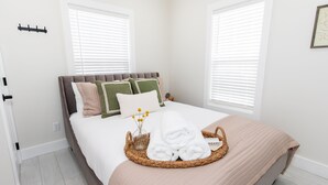 A neatly made bed with a brown headboard, white bedding, and a beige throw blanket.