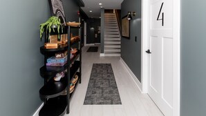 A hallway with a black bookshelf, a patterned rug, and a white door with the number 4.