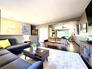 A modern living room with a sofa, a coffee table, and a dining area.