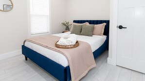 Une chambre à coucher avec un lit, une table de chevet, une fenêtre avec des stores et une porte.