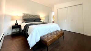 Ein Schlafzimmer mit einem Bett, Nachttischen, einer Bank und einem Kleiderschrank.