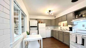 A compact kitchen with white appliances, grey cabinets, and a wooden floor. - Stylish 2BR in Historic WaterHill / Walk to Downtown & The Big House (Ann Arbor)