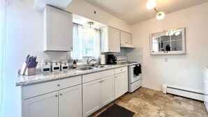 A modern kitchen with white cabinets, a granite countertop, a built-in oven, and a window with curtains.