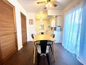 Una cucina compatta con zona pranzo, porte in legno e ventilatore a soffitto.