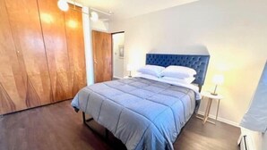 A bedroom with a bed, wooden wardrobe, and a bedside table with a lamp.
