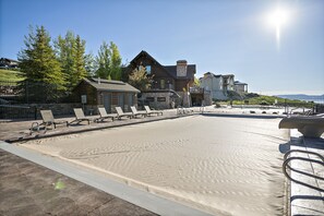 Relax by the serene pool, surrounded by lush greenery and a rustic resort building.