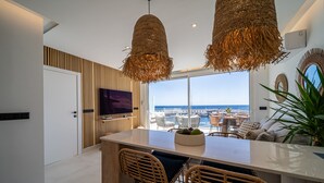 A modern kitchen with a large island, wicker chairs, and a view of the sea. - Luxury on the Seafront (Tías)