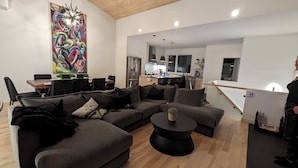 A modern living room with a sectional sofa, a round coffee table, and a vibrant abstract painting.