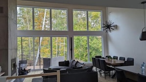 A modern living room with a large window, a dining area, and a fireplace.