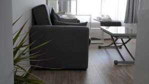 A modern living room with a grey sofa, a small table, and a plant. - Lux Studio Nerja (Nerja)