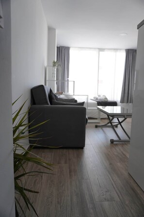 A modern living room with a grey sofa, a small table, and a plant. - Lux Studio Nerja (Nerja)