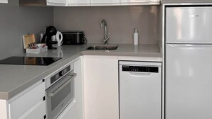 A modern kitchen with white cabinetry, a built-in oven, a dishwasher, and a stainless steel refrigerator. - Lux Studio Nerja (Nerja)