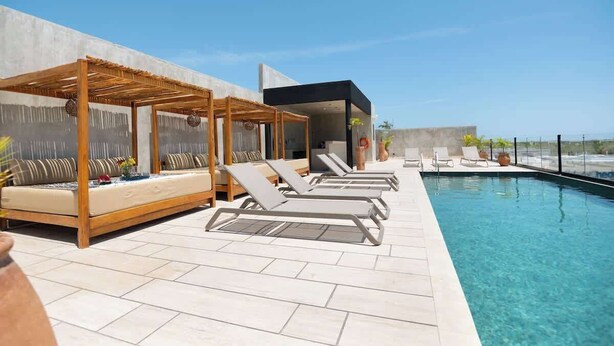 A rooftop pool area with lounge chairs and a covered seating area. - Design apt - Unbeatable location - pool - GYM (Tulum)