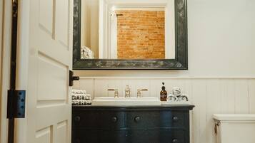 A bathroom with a white door, a black vanity with drawers, a mirror above the sink, and a white toilet.