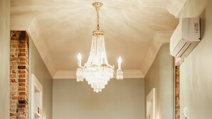 A hallway with a chandelier, a white door, and brick walls.