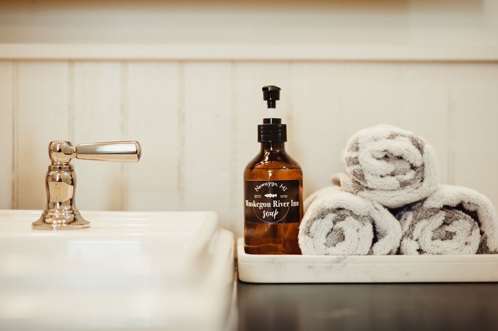 Une salle de bain équipée d’un lavabo, d’un distributeur de savon et de serviettes pliées.