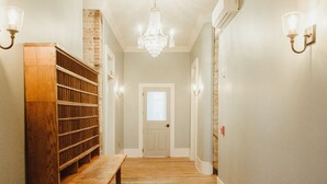 A hallway with a wooden bench, a chandelier, and wall sconces.