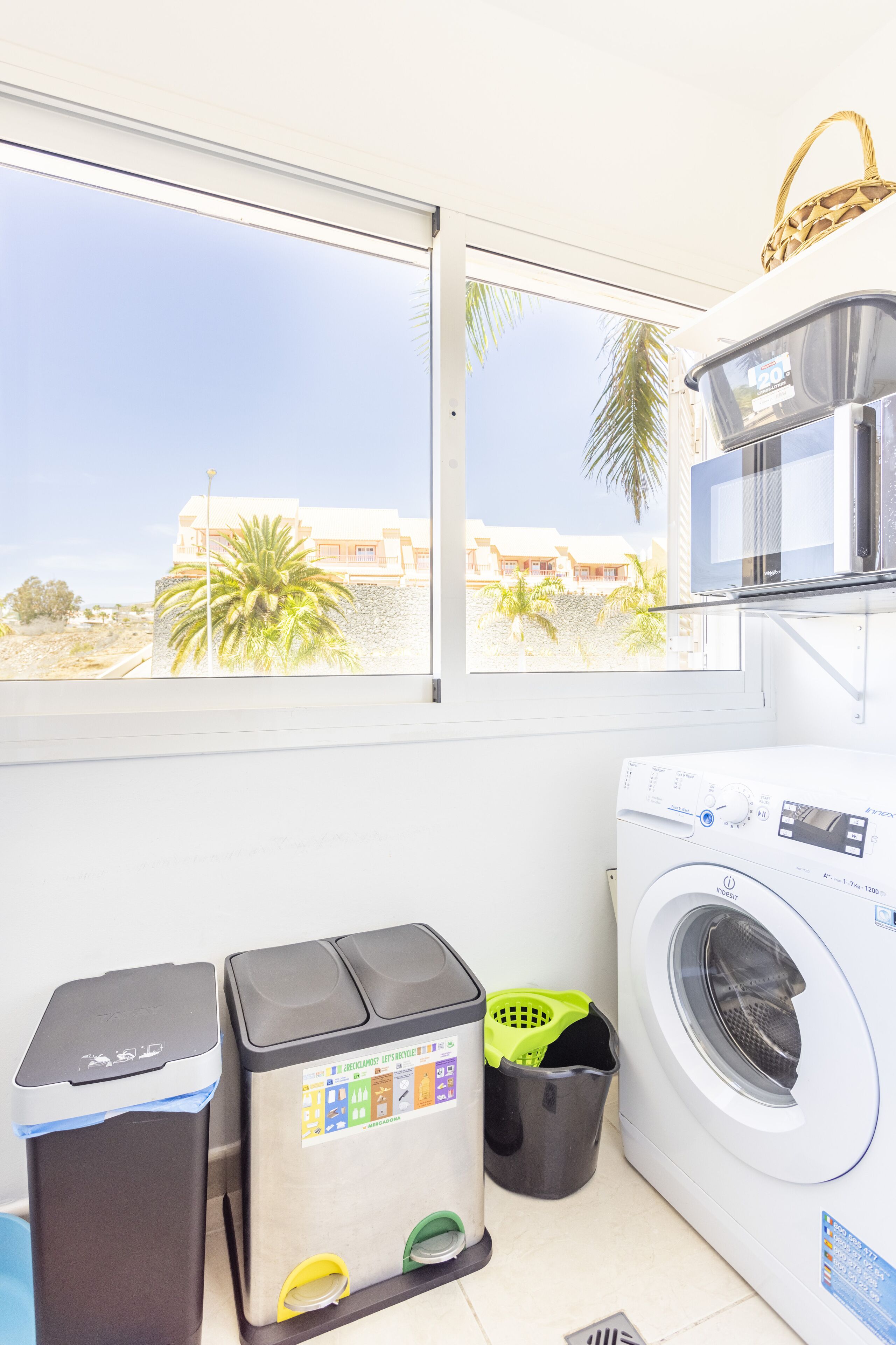 A laundry area with a washing machine, a trash bin, and a recycling bin.