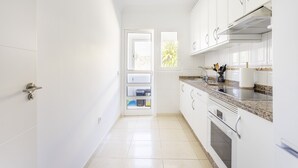 Una cocina moderna con armarios blancos, encimeras de granito y electrodomésticos de acero inoxidable.