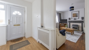 A living room with a white door, a fireplace, a sofa, and a coffee table. - Relax in comfort in Chingford! (Greater London)