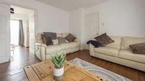 A living room with two beige sofas, a wooden coffee table with a plant, and a patterned rug. - Relax in comfort in Chingford! (Greater London)