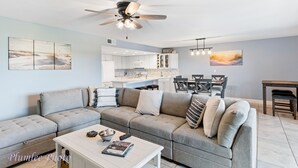 A modern living room with a sectional sofa, a dining area with a table and chairs, and a kitchen in the background. - Holiday Villas II 408 - INTERCOASTAL (Indian Shores)