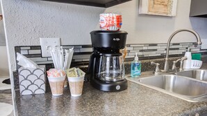 A kitchen counter with a coffee maker, two cups of coffee, a tissue box, and a bottle of hand soap. - La Palma Guesthouse (Lubbock)