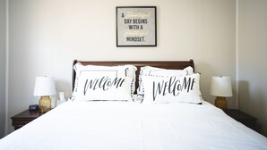A neatly made bed with two pillows that say "WELCOME" and a motivational quote on the wall above. - La Palma Guesthouse (Lubbock)