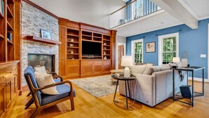 A spacious living room with a fireplace, wooden shelving, a television, and a sofa. - Lakefront Moose Pond Retreat (Denmark)