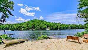 A sandy beach with a wooden bench and a boat docked on the shore. - Lakefront Moose Pond Retreat (Denmark)