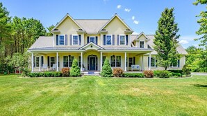 A two-story house with a front porch, a covered entryway, and a well-maintained lawn. - Lakefront Moose Pond Retreat (Denmark)