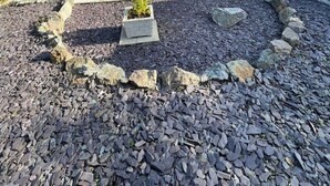 A two-story house with a grey exterior, a tiled roof, and a front garden with a gravel pathway and potted plants. - Peaceful centrally located, 2- Bedroom Bungalow. (Pengegon)