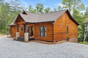 A log cabin with a stone porch, a chimney, and a gravel driveway. - Hidden Haven- Welcome to Modern Living! (Morganton)