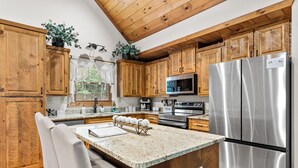Cucina con pensili in legno, elettrodomestici in acciaio inossidabile e piano di lavoro in granito.