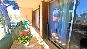 Un balcon avec un pot de fleurs, une chaise et une porte-fenêtre coulissante.