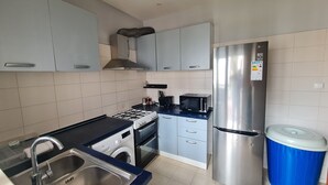 Een moderne keuken met een gasfornuis, magnetron, oven en een roestvrijstalen koelkast.