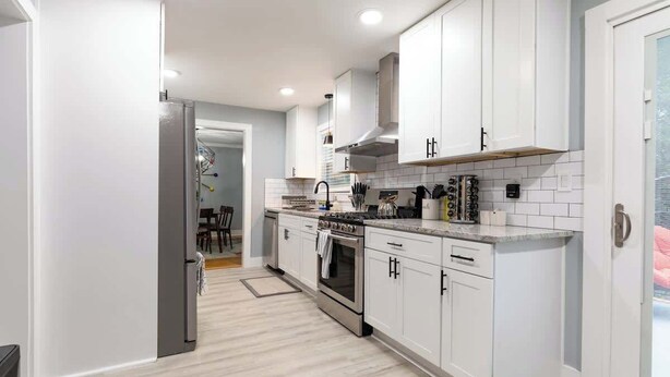 A modern kitchen with white cabinets, a stainless steel refrigerator, and a built-in oven.