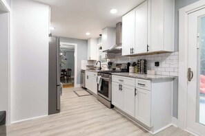 Una cocina moderna con armarios blancos, un refrigerador de acero inoxidable y un horno empotrado.
