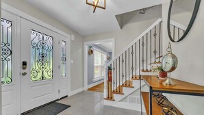 A modern interior with a staircase, a wooden bench, and a decorative mirror.