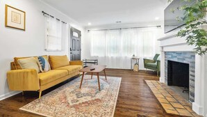 Een woonkamer met een gele bank, een salontafel, een open haard en uitzicht op de omgeving.