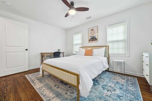 A bedroom with a bed, a desk, a chair, a dresser, a ceiling fan, and a window with blinds. - Modern Boho w/ 3BR/5BD Sleeps 10 (Atlanta)