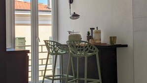 A modern kitchen with two bar stools, a black countertop, and a window with a view of buildings. - MORET HOUSE (Sanremo)