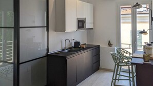 A modern kitchen with a black and white color scheme, a built-in microwave, and a large window providing natural light. - MORET HOUSE (Sanremo)