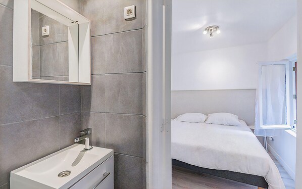 A modern bathroom with a white sink, mirror, and a shower area.