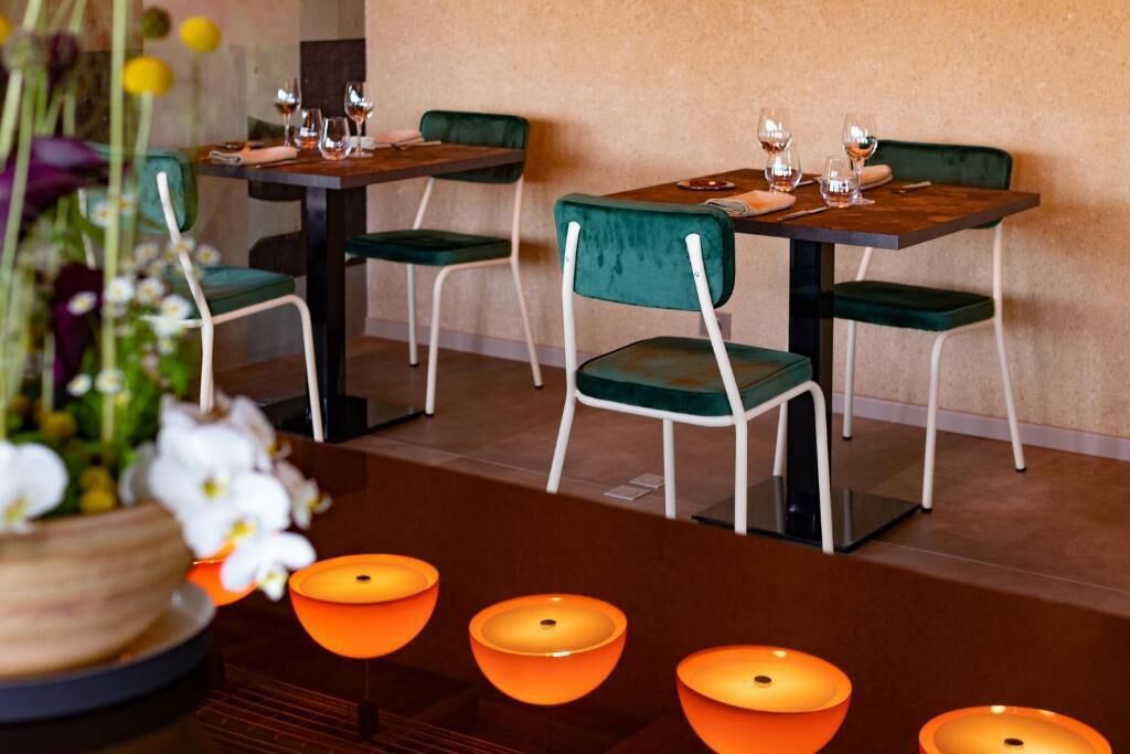 Un'area pranzo con tavoli e sedie, un vaso con fiori e lampade da tavolo arancioni.